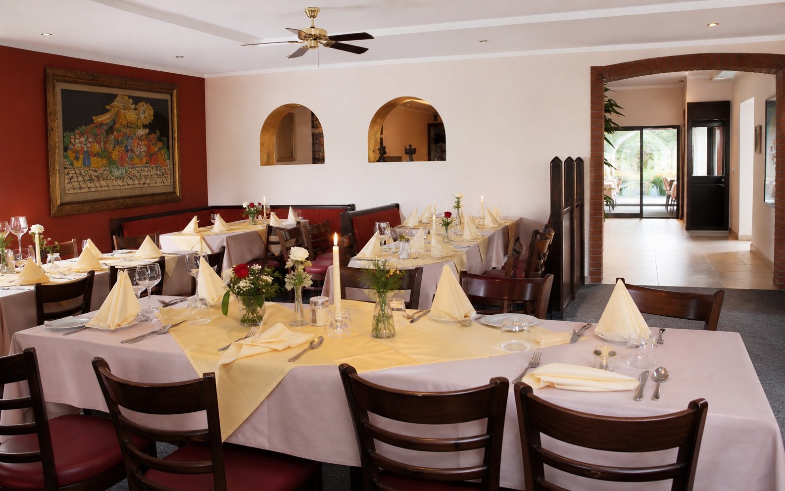 Festlich eingedeckte Tafel für eine Feier mit gelben Tischläufern, Kerzen und Blumenschmuck im Restaurant Santa Lucia